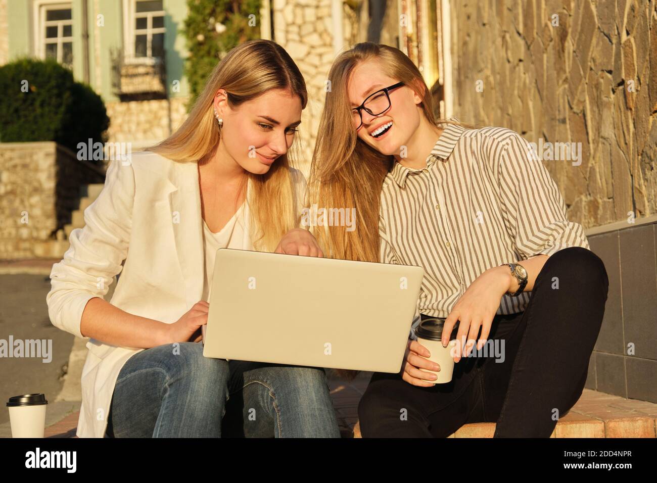 Two young beautiful women having fun looking into the laptop monitor ...