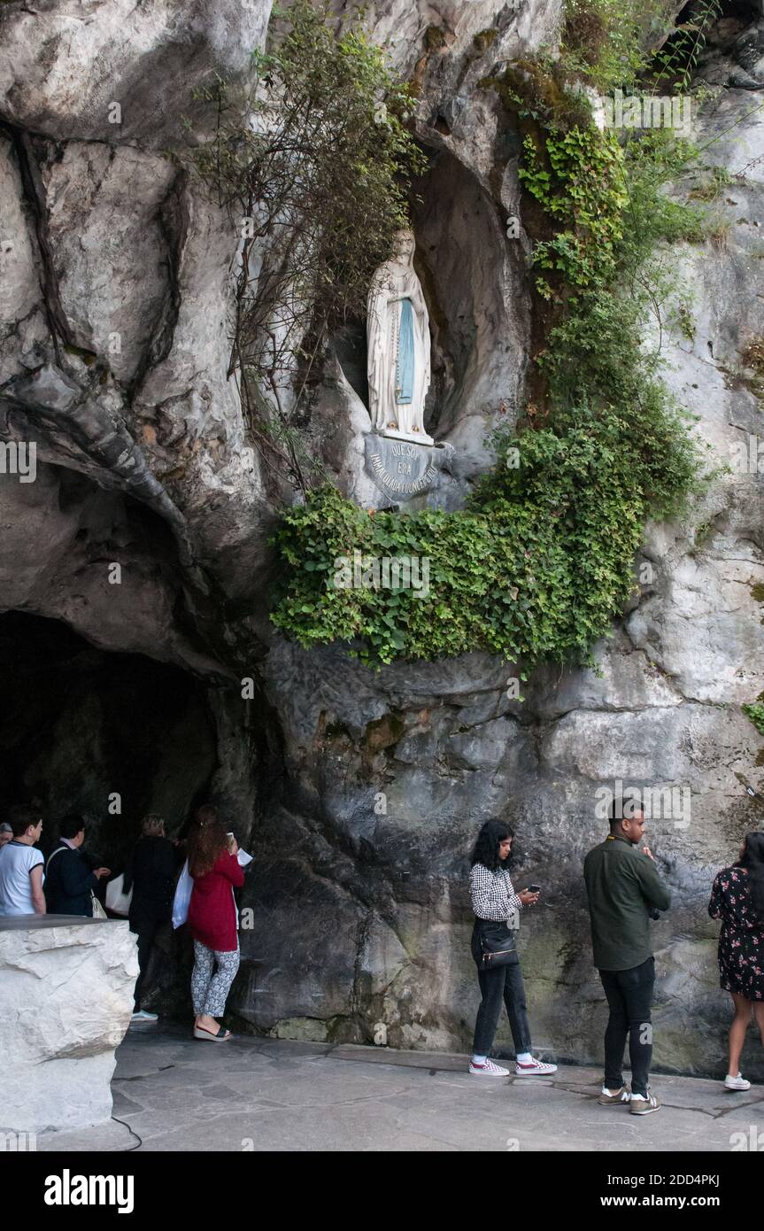 Pilgrims at the exit of the grotto, overhung by the statue of the ...