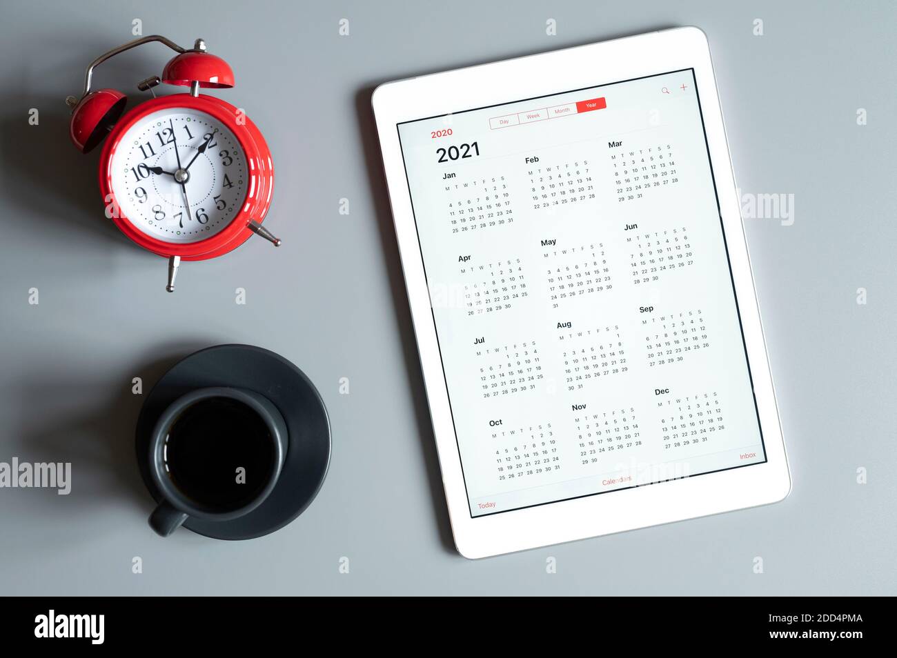 a tablet with an open calendar for 2021 year, a cup of coffee, and a ...