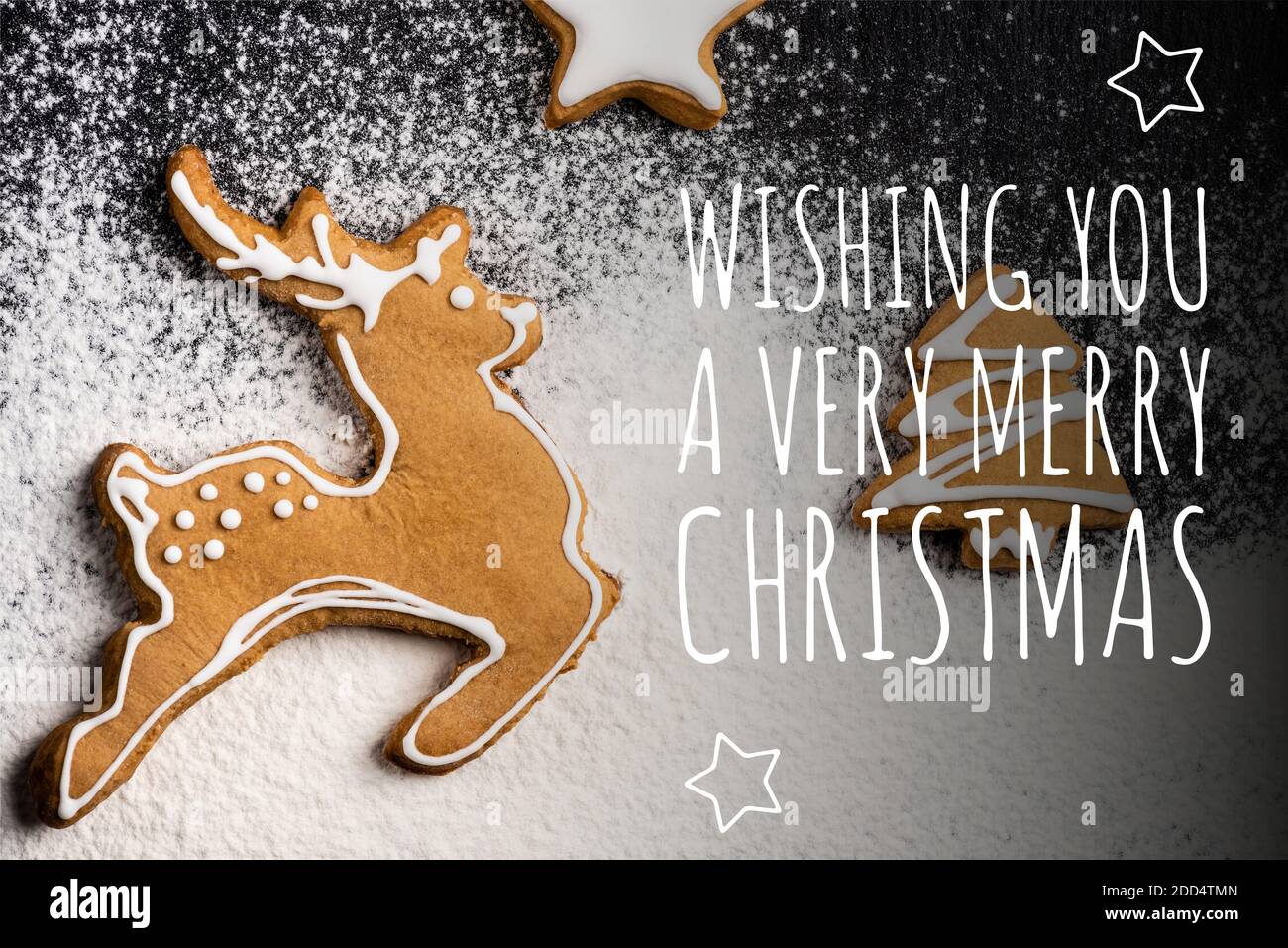 Top view of cookies in shape of deer, pine and star near wishing you a very merry christmas lettering and sugar powder Stock Photo