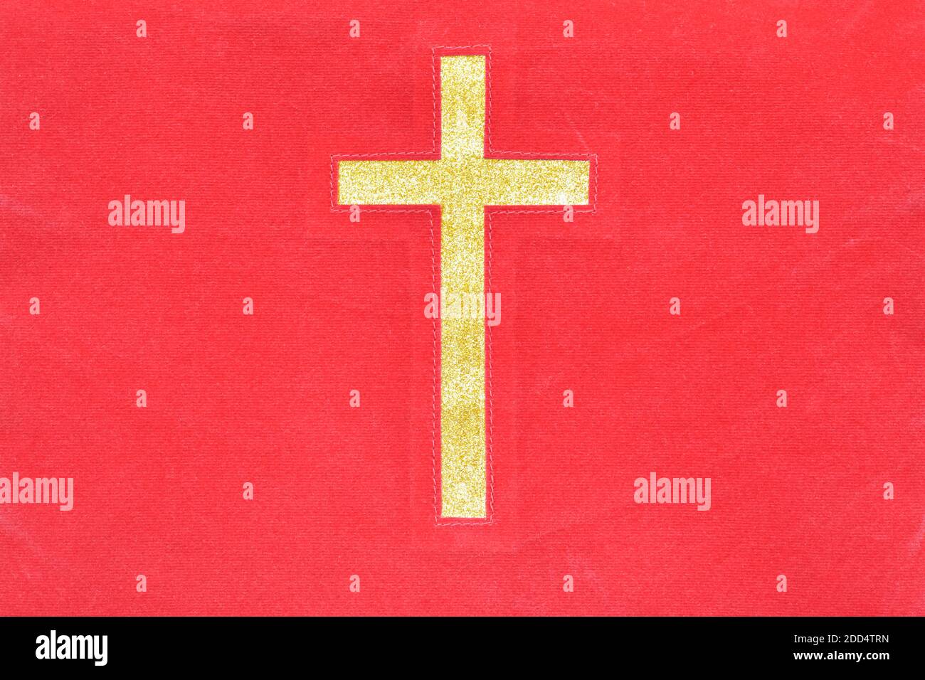 Gold catholic cross on red cloth texture background. Stock Photo