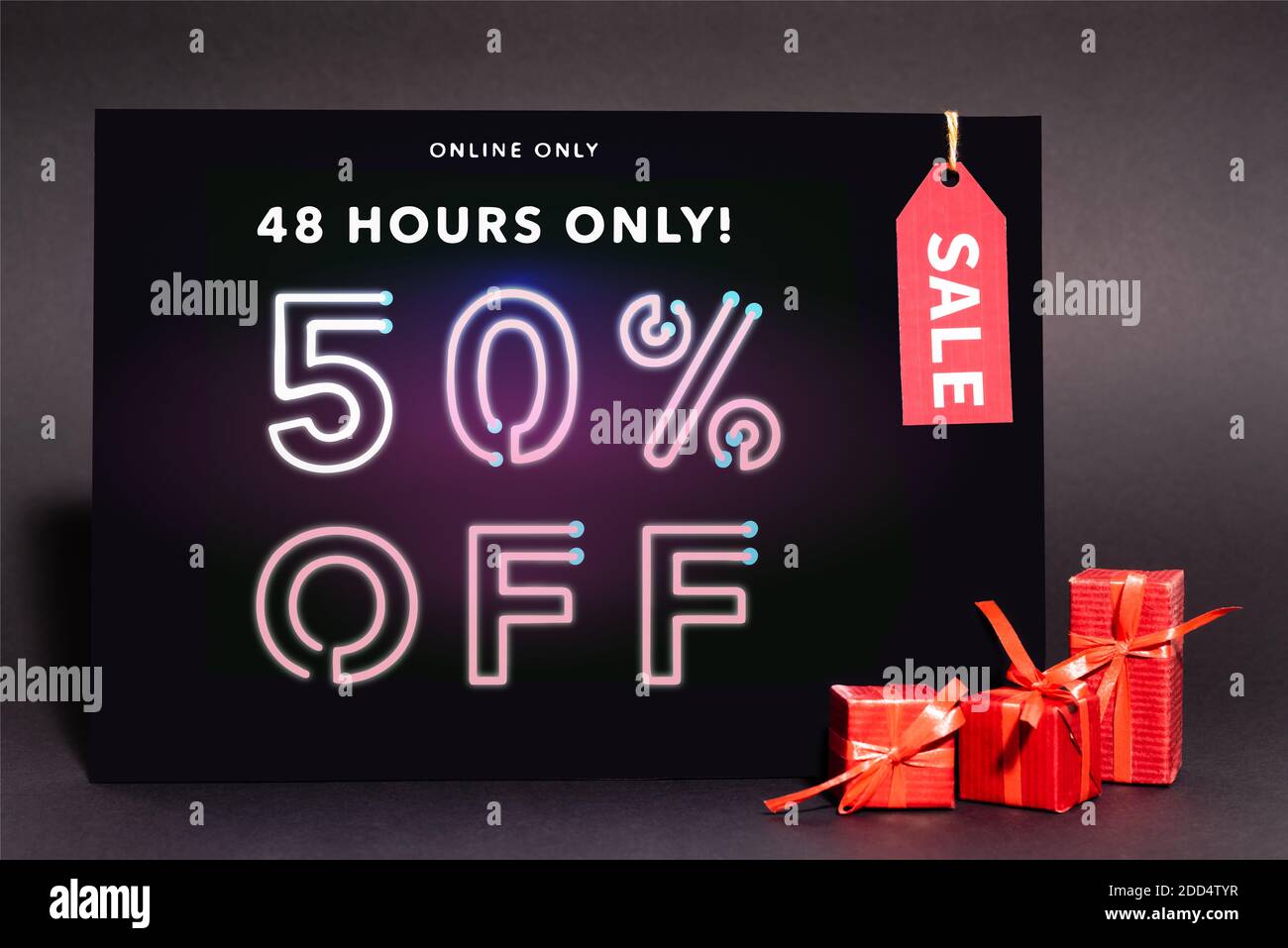 placard with online only, 48 hours only, 50 percent off lettering and sale tag near presents on dark background Stock Photo