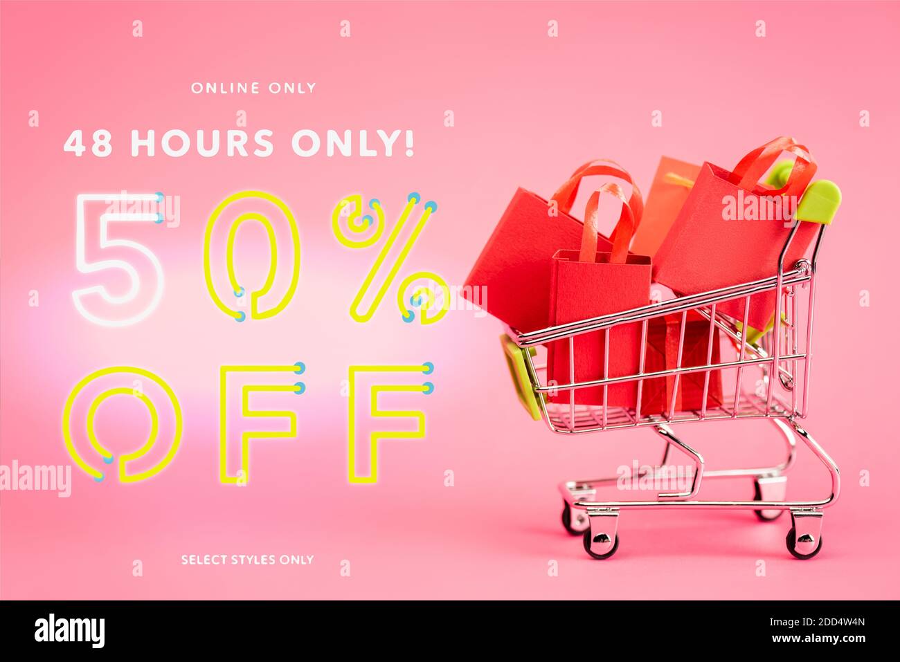 shopping bags in small trolley near online only, 48 hours only, 50 percent off, select styles only lettering on pink, black friday concept Stock Photo