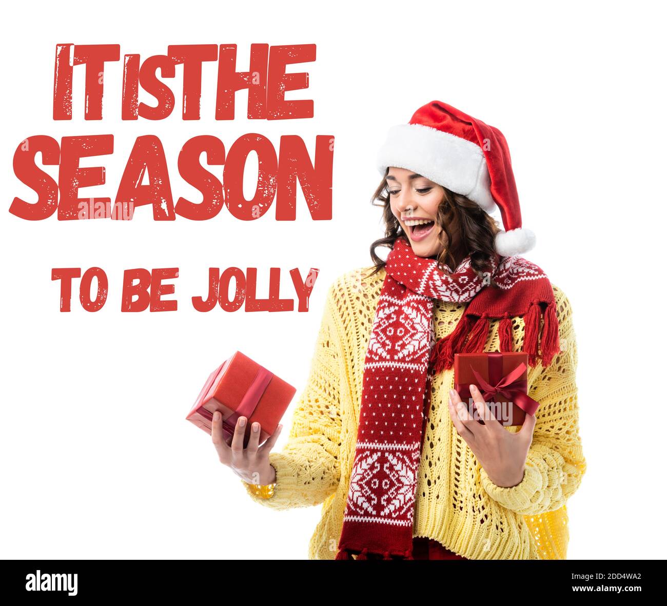 excited woman in santa hat and red scarf looking at present near it is the season to be jolly lettering on white Stock Photo