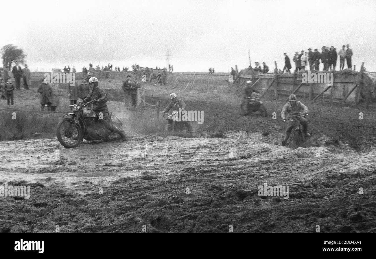 1950s, historical, motorcycle scrambling......competitors on motorcycles taking part in a scrambling or motorcross race on a muddy circuit.  Camberley in Surrey was the venue of the first scramble race in 1924. In the following years, the sport grew in popularity, especially in Britain where teams from the classic British motorcycle manufacturers, including the Birmingham Small Arms Company (BSA), Norton, Matchless, Rudge, and AJS competed in races. Stock Photo