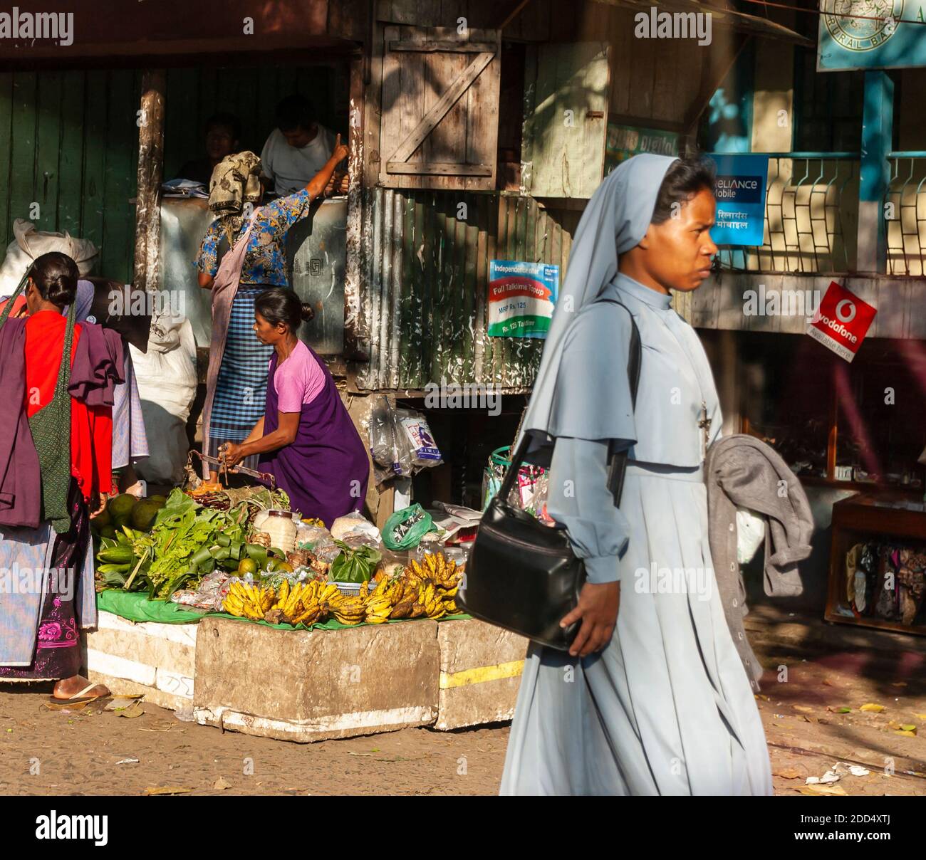 A nun walks by a roadside market on the Shillong-Guwahati highway, Meghalaya, India. Stock Photo