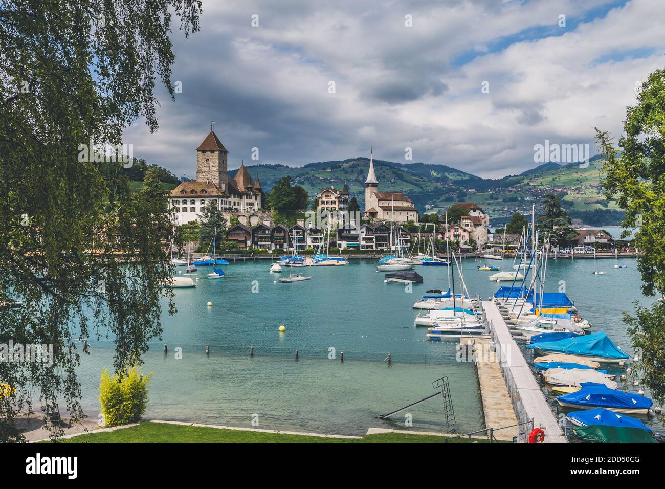 View on beautiful small city, lake Thun, marine and many boats. City of Spiez, canton Bern, Switzerland. Haze effect Stock Photo