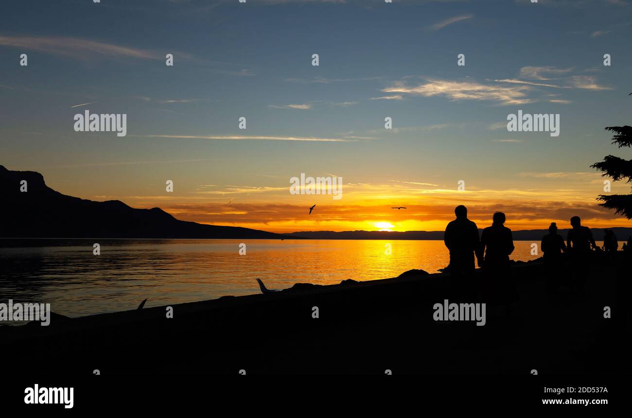 Sunset Silhouette. People near the Geneva Lake And Beautiful Sunset Over The Lake On The Background. Stock Photo