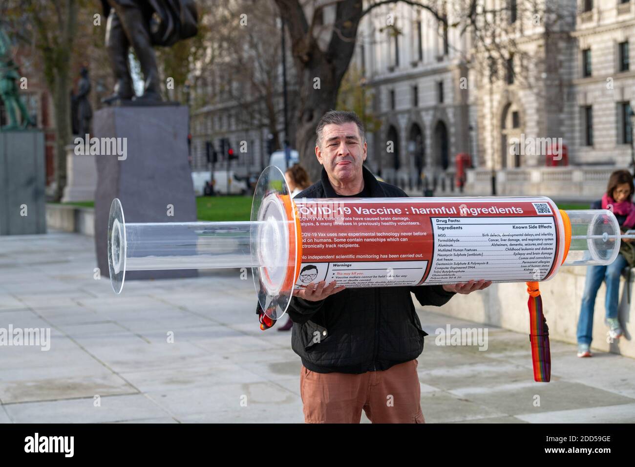 London, UK. 24th Nov, 2020. Piers Corbyn, (brother of former Labour leader Jeremy Corbyn) led a small anti vax anti mask protest and handed out mask exemption cards to passers by and the media. He was accompanied by a man carrying a giant syringe, who was subject to questioning by police on Westminster Bridge. Credit: Ian Davidson/Alamy Live News Stock Photo