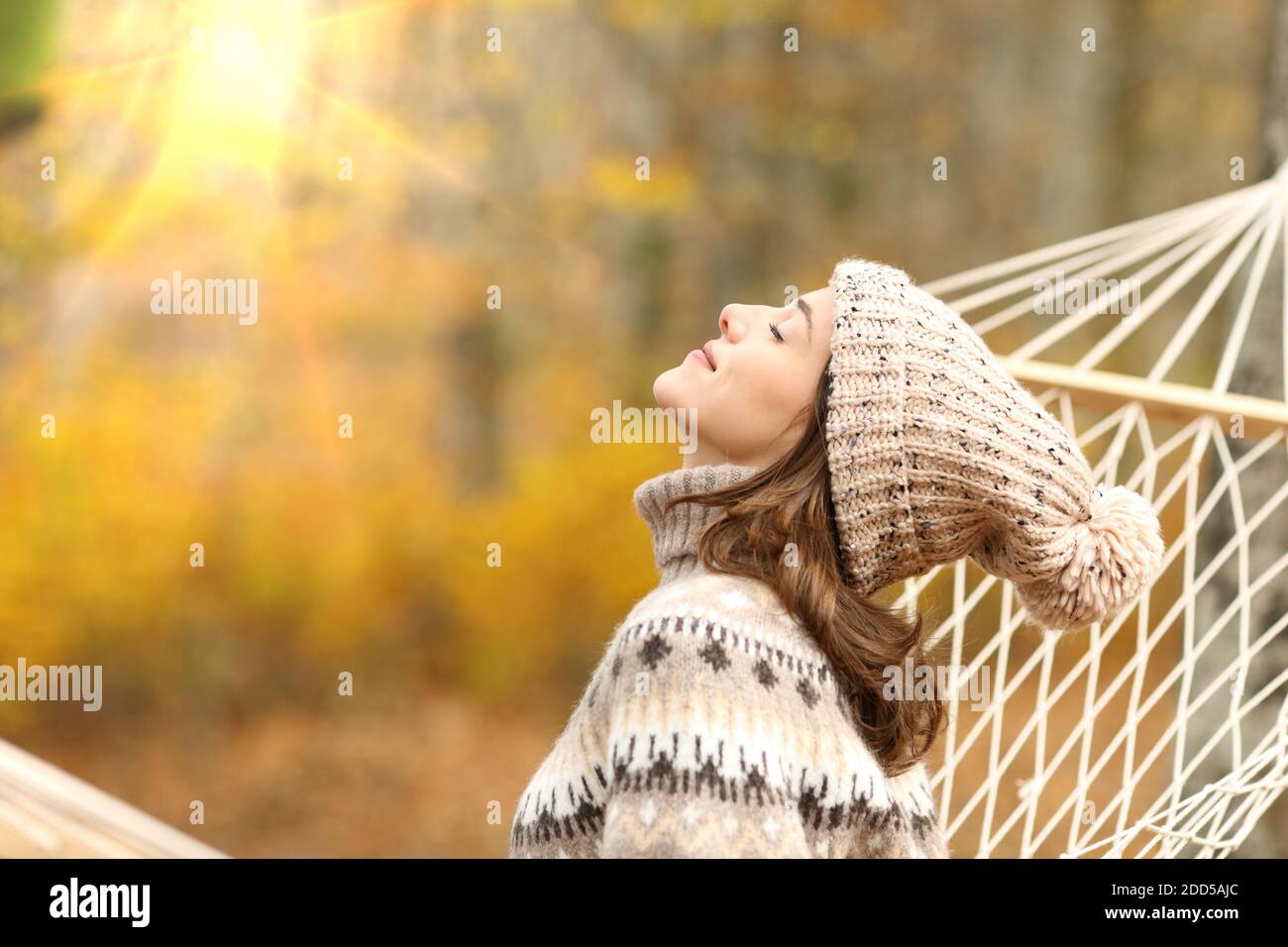 Side view portrait of a relaxed woman breathing fresh air sitting on a rope hammock in autumn in a forest Stock Photo