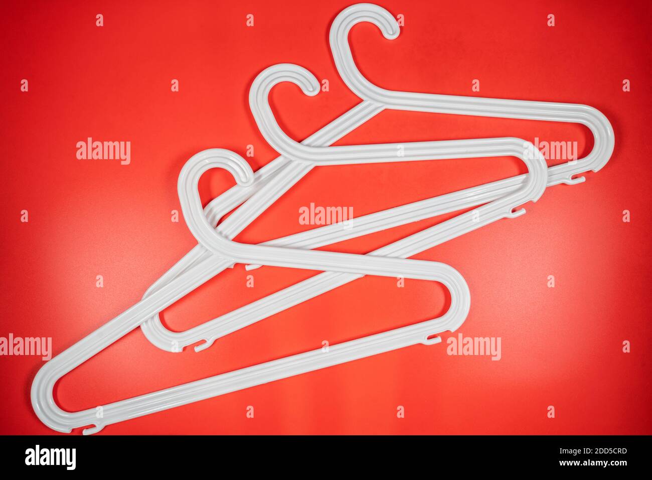 Plastic white coat hangers clothes hanger on a red background Stock Photo Alamy