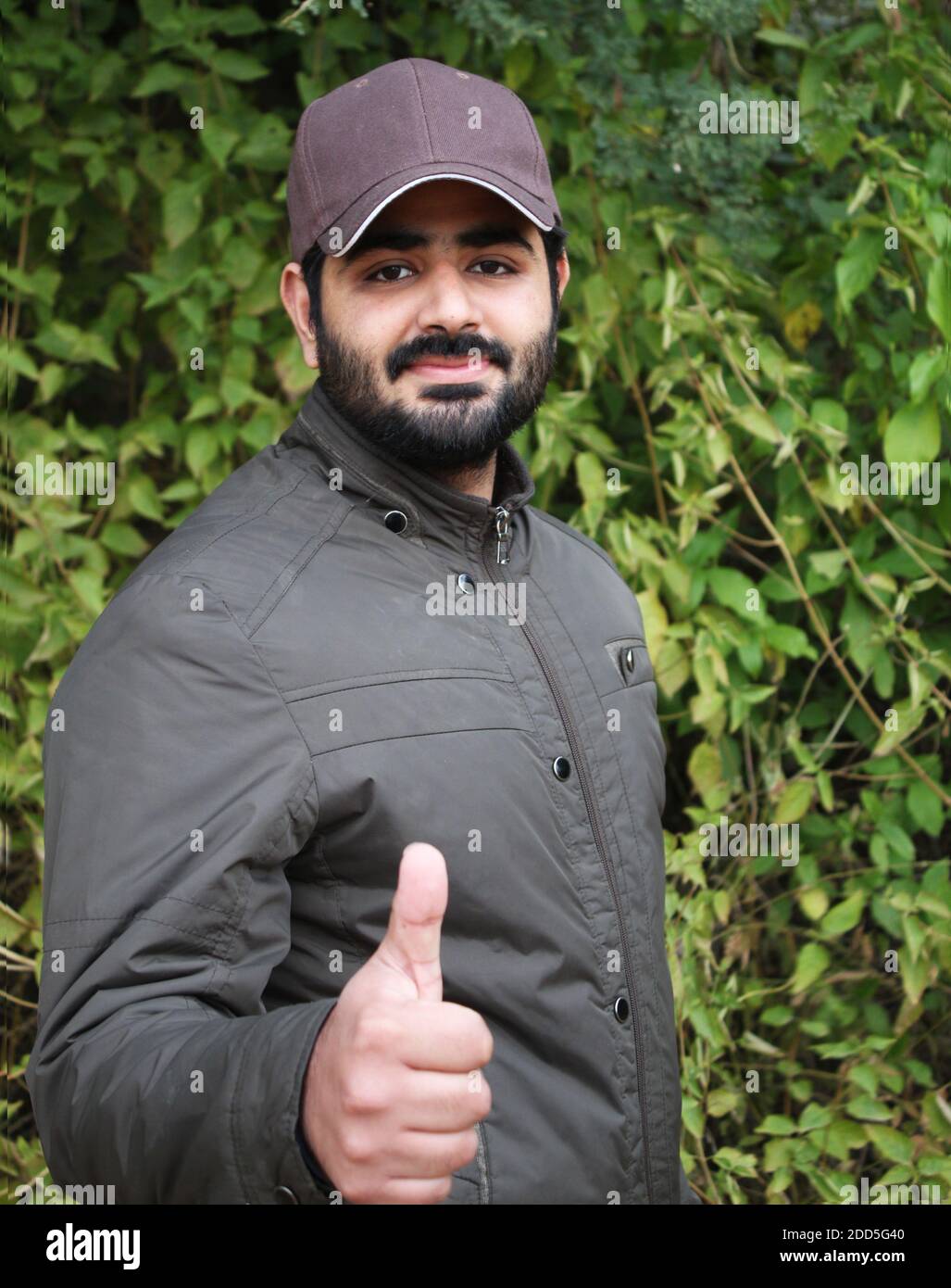 Portrait of a young handsome man showing thumbs up in the forest Stock Photo