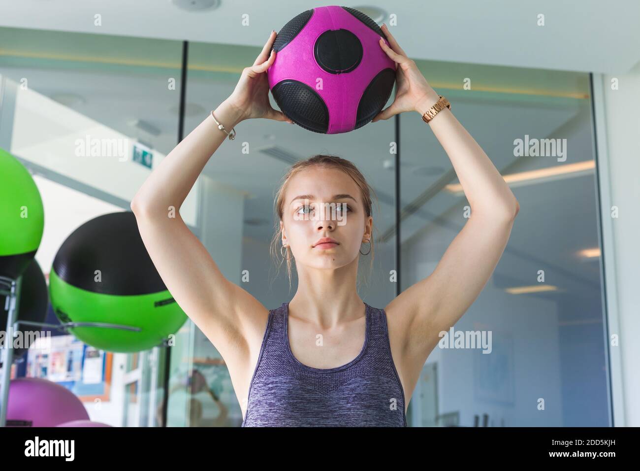 Young blond sporty girl does an exercise with med ball in a gym Stock Photo