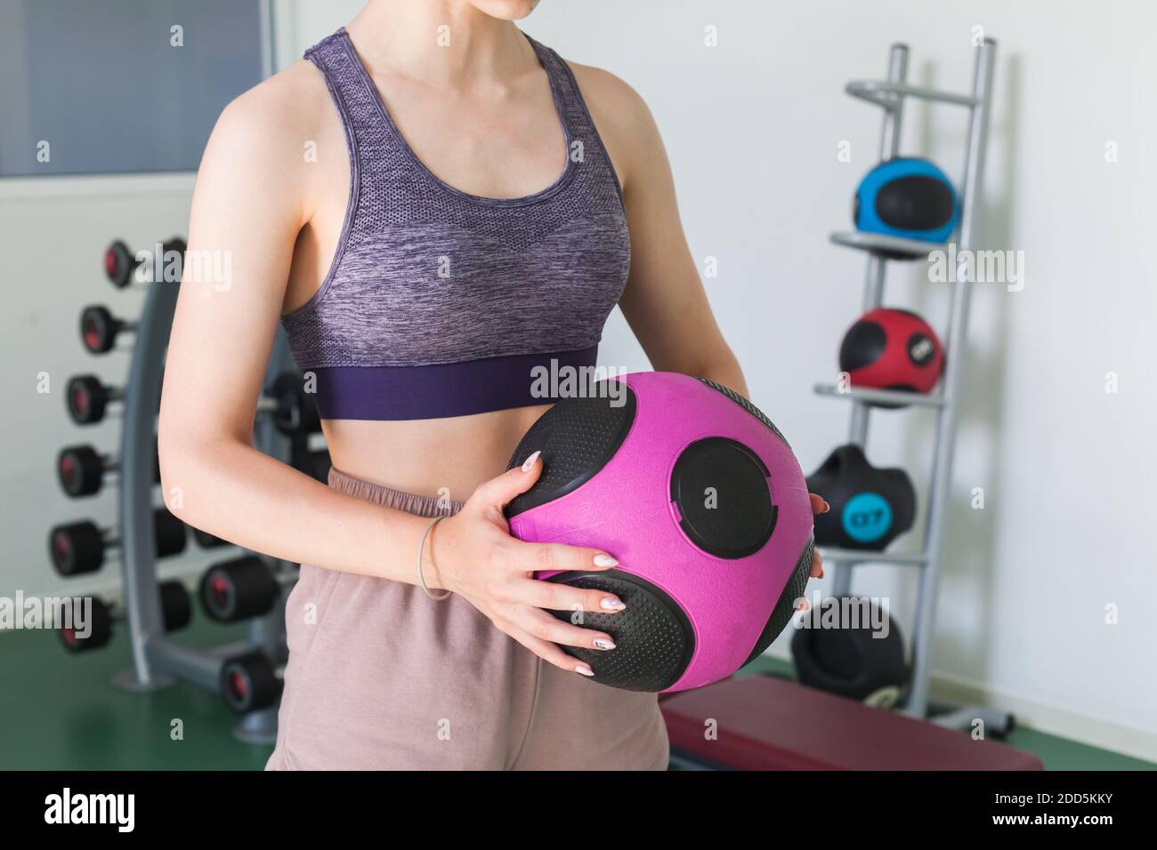 Sporty girl holds in her hands black pink med ball in a gym Stock Photo