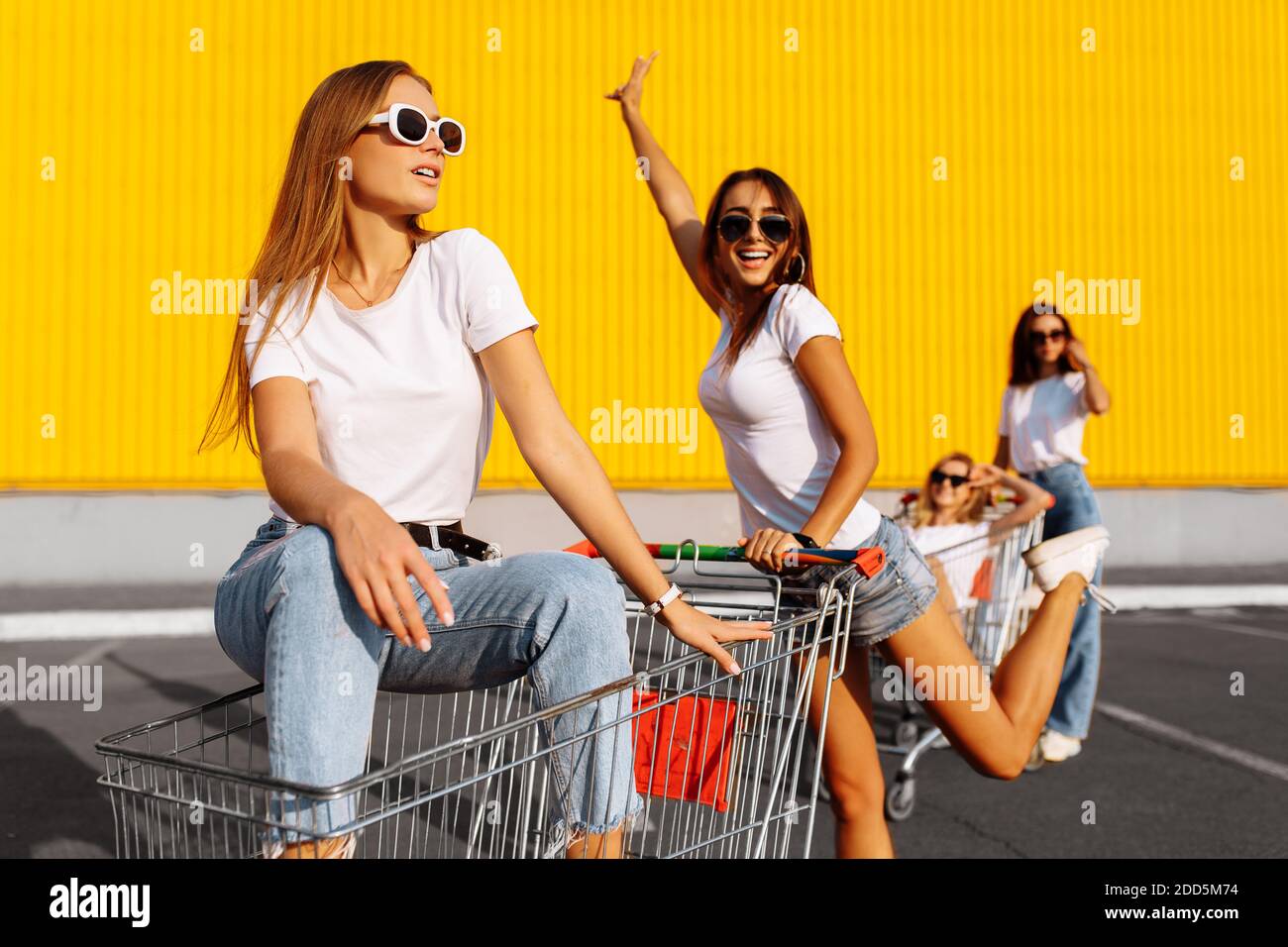 Young friends have fun on shopping carts, girlfriends ride together on