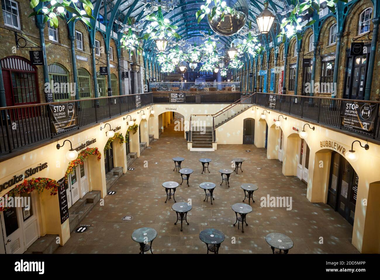 London, UK. - 21 Nov 2020: Socially distanced tables - due to the coronavirus pandemic - sit under this years Christmas decrorations at Covent Garden. Stock Photo