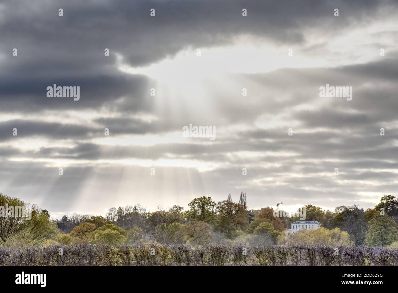 Sun rays through a dark cloud in this photo taken from the meadow at Runnymede in Egham on an overcast autumn day Stock Photo