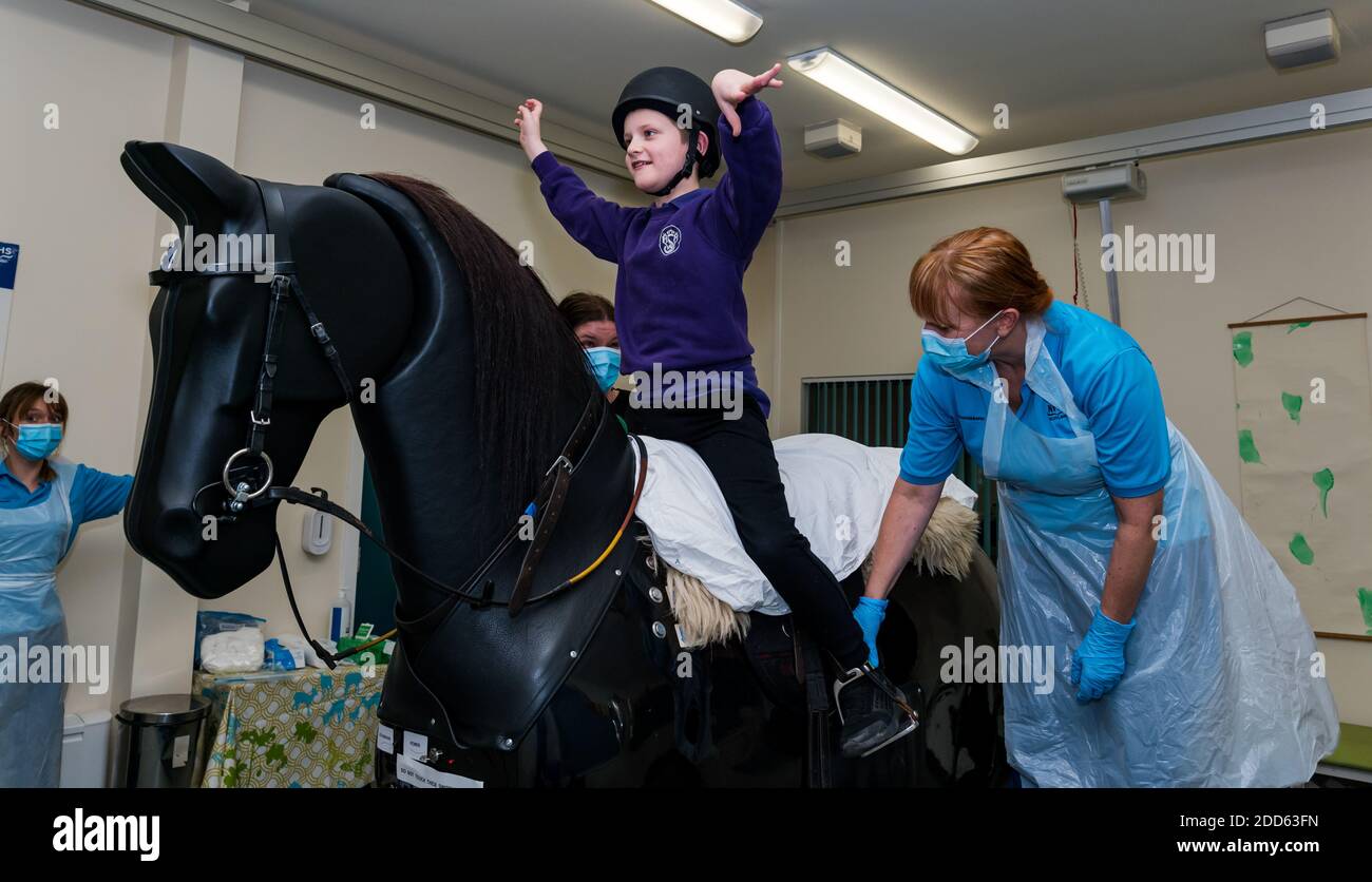 East Lothian, Scotland, UK, NHS Lothian & Muirfield Riding Therapy celebrates 10 years of Hippotherapy:  Physiotherapist Heather Falconer pioneered The Children’s Therapeutic Riding Service providing therapeutic riding free of charge to children, young people and adults with disabilities. The service was the first in Scotland for children with mobility, balance, muscle tone and coordination problems. Oreo, a mechanical horse, allows youngsters to have fun physiotherapy. Kyle Clark, aged 8 years, rides the Racewood mechanical horse simulator Stock Photo