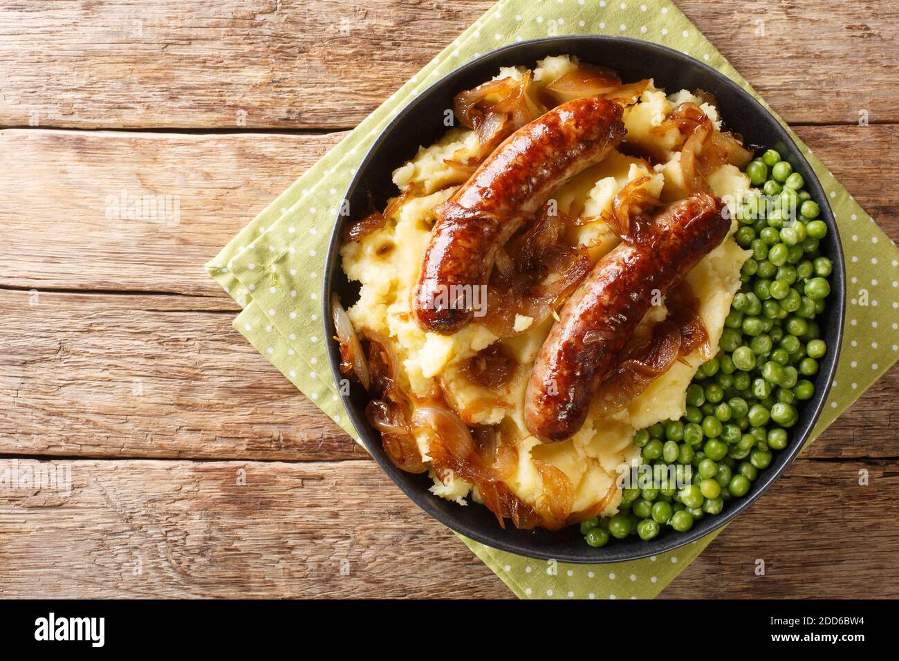 Fried sausages with mashed potatoes, onion gravy and green peas close