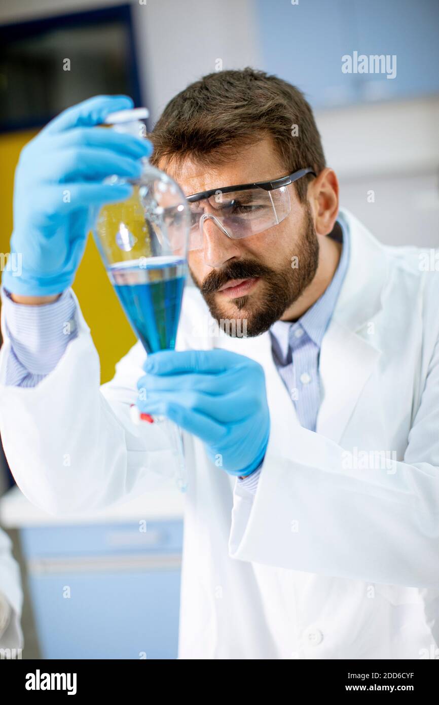 Researcher working with blue liquid at separatory funnel in the
