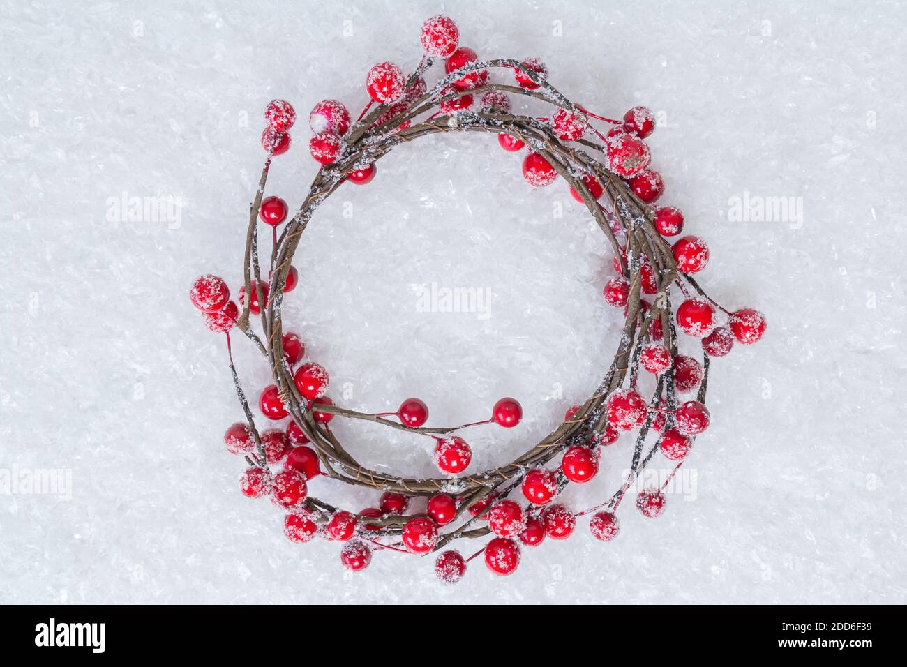 Christmas wreath of twigs with red holly berries on white snow background. Holiday berry wreath. Winter holiday theme. Happy New Year. Copy space for Stock Photo