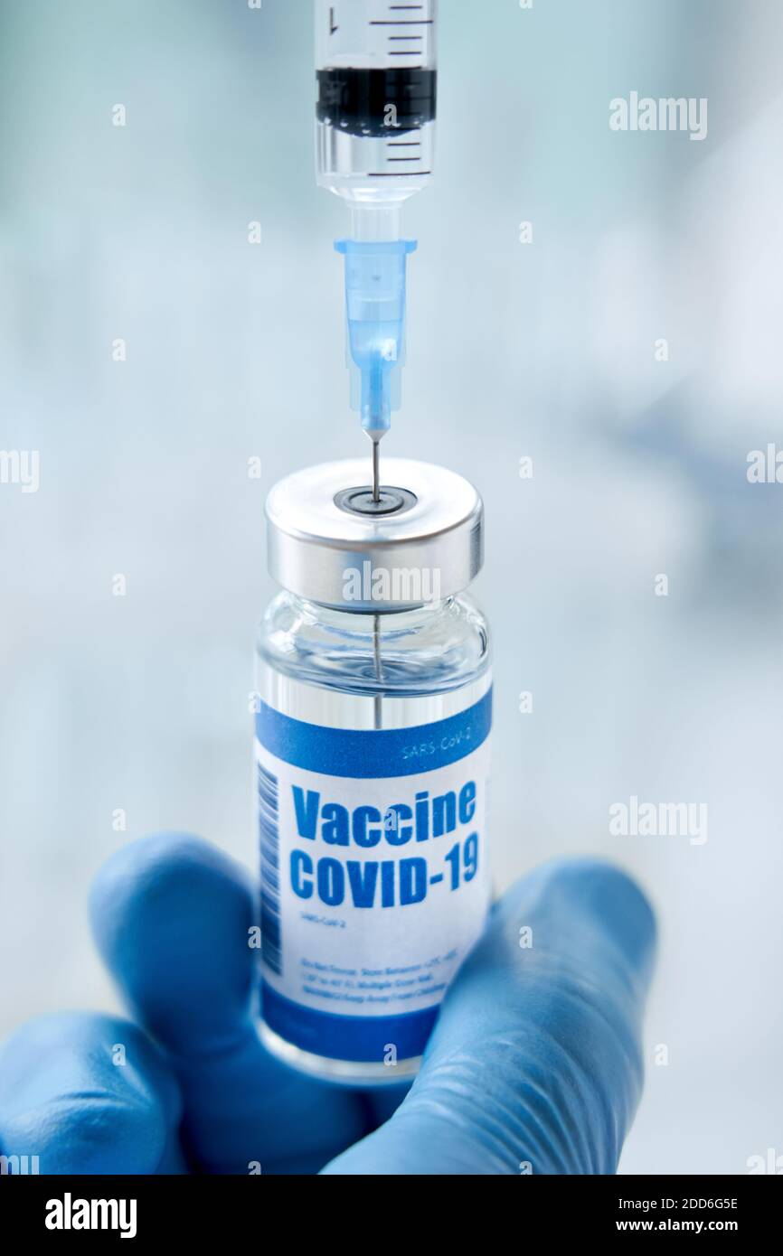 Male doctor or scientist hand holding syringe taking covid 19 vaccine from vial. Stock Photo