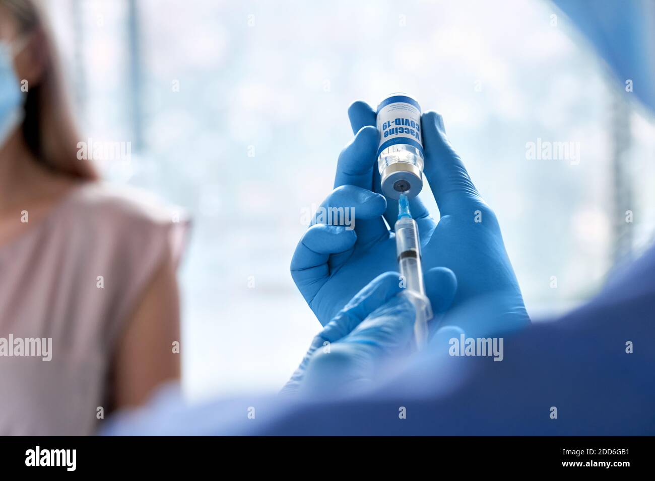 Male doctor holding syringe taking coronavirus vaccine for patient vaccination. Stock Photo