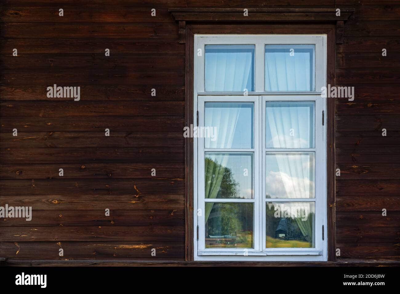 Rectangular window with a white frame against a wall of dark brown ...