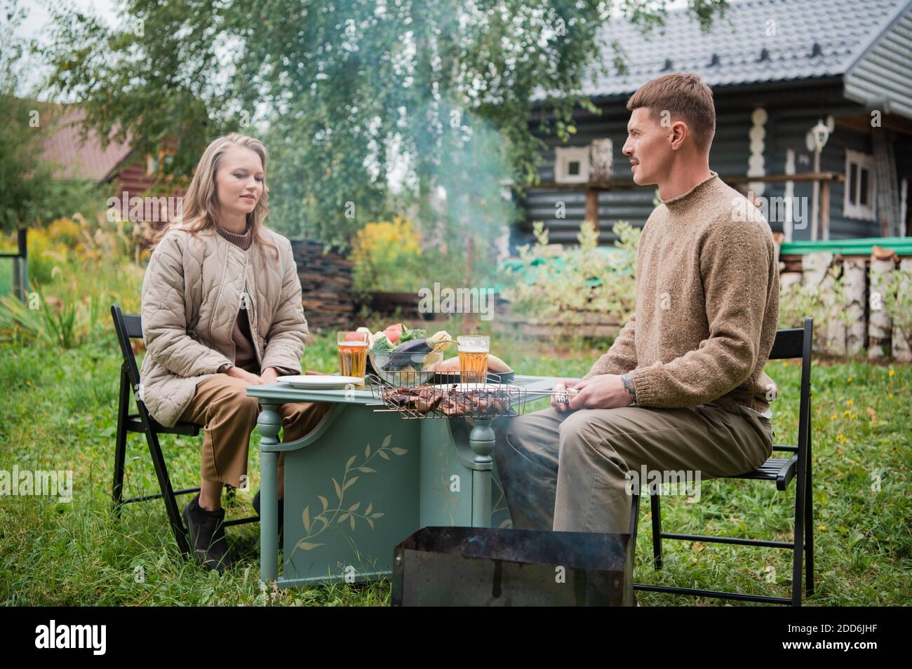 A young man is courting his fiancee. He puts chunks of grilled meat