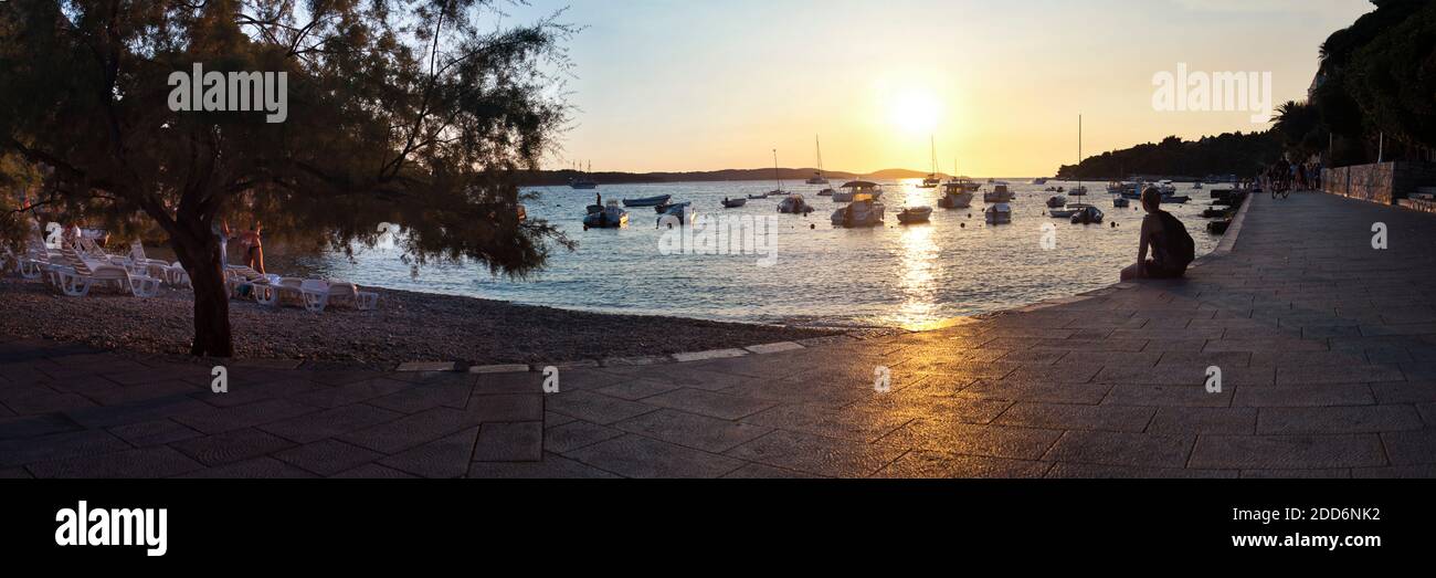 Panoramic photo of a tourist sitting watching the sunset in Hvar Town ...