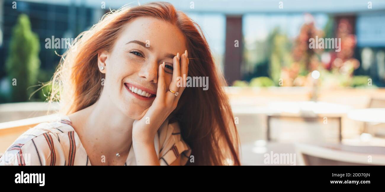Lovely ginger lady covering her face with freckles and smiling at camera Stock Photo