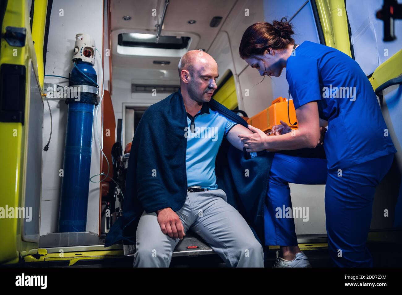 A young nurse in a uniform giving an injection to a patient in an ...