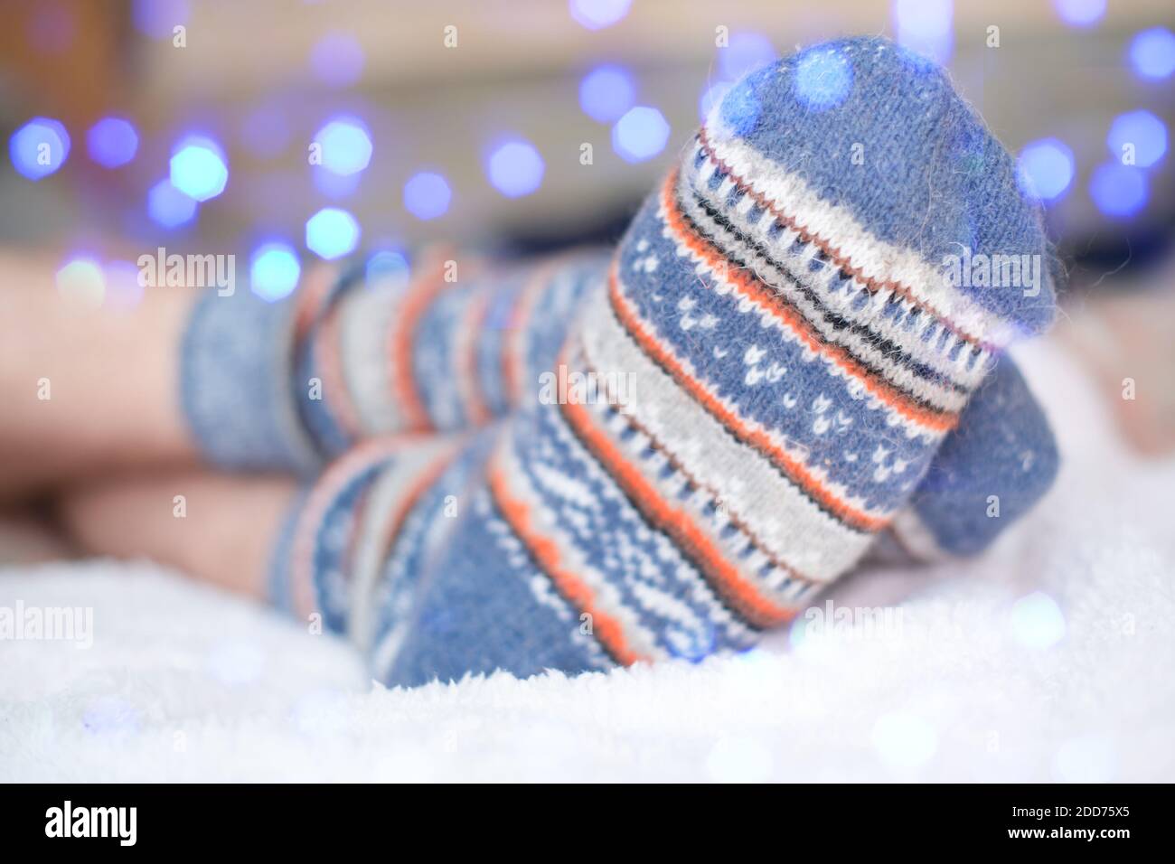 Feet of a young man in warm wool socks with a Scandinavian pattern. Comfort and coziness on a cold winter day at home.  Stock Photo