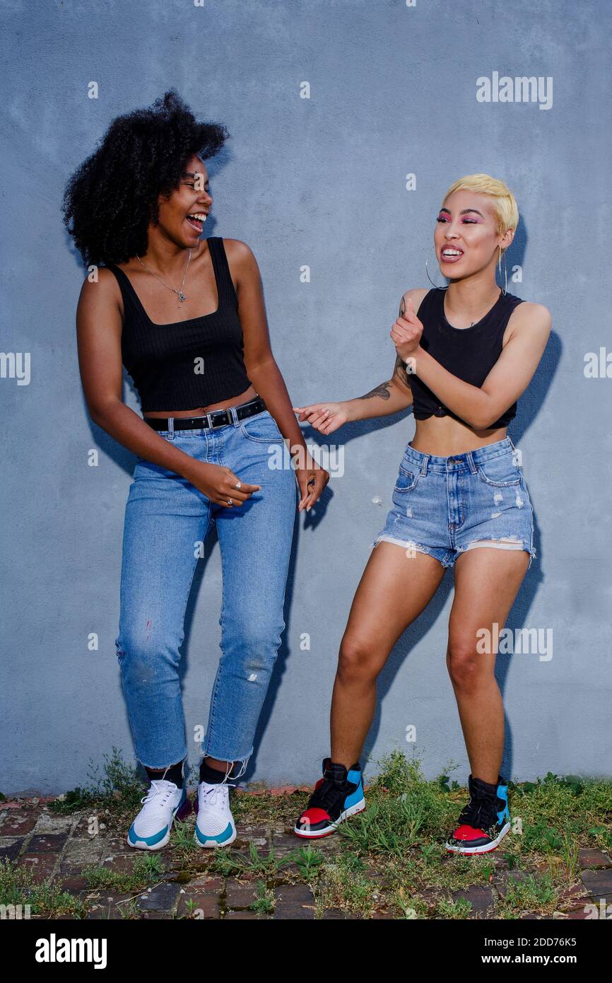 Two laughing friends in matching clothes dance together outside Stock Photo