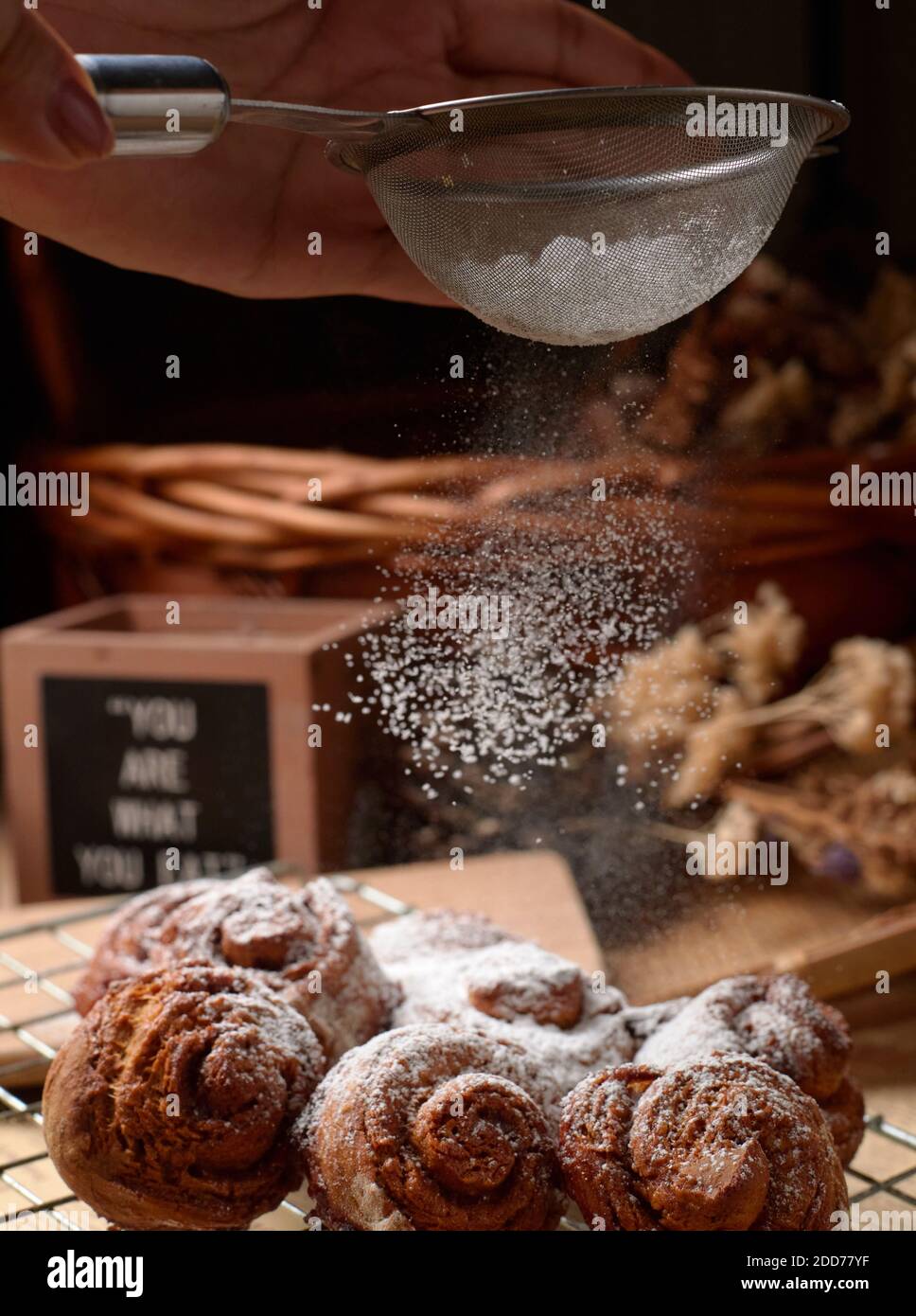 Close Up view chef sprinkle icing sugar over the cinnamon rolls Stock Photo