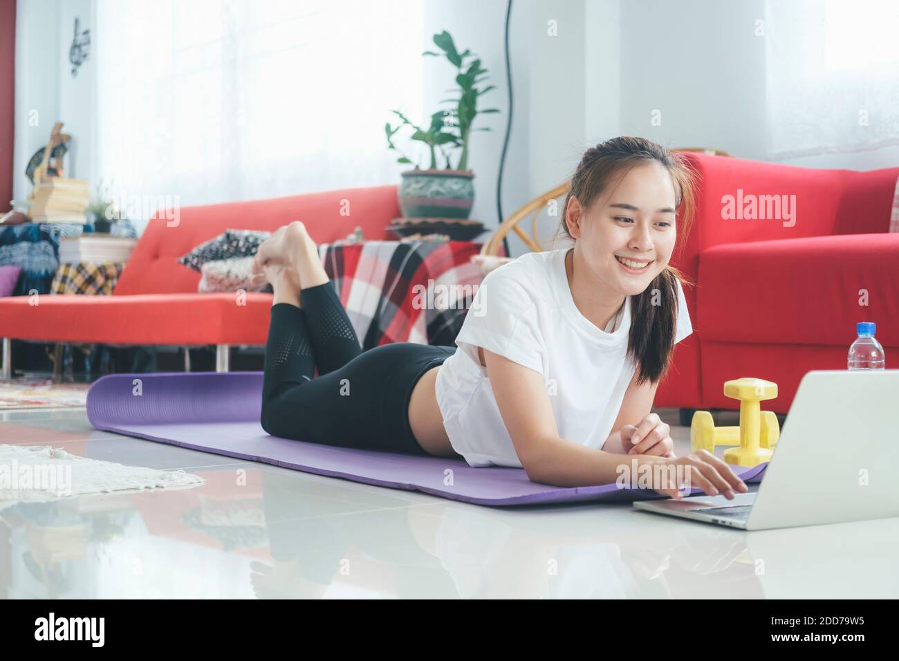 Happy woman open online tutorial on computer laptop for her exercise at home in livingroom. Stay at home and healthy lifestyle. Stock Photo