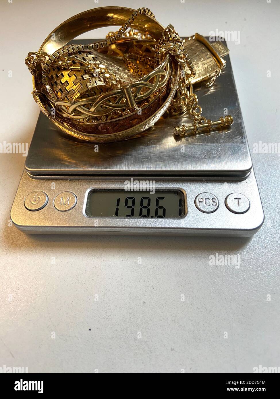 Gold scrap pile chains and bangle jewelry on scale being weighed at