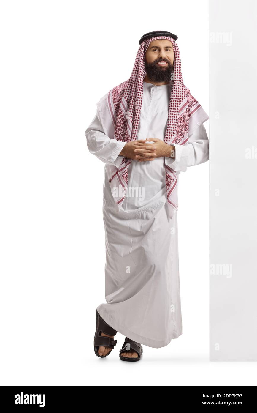 Full length portrait of a saudi arab man wearing a traditional thobe and leaning on a wall isolated on white background Stock Photo