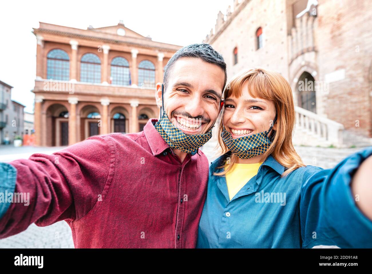 Happy boyfriend and girlfriend in love taking selfie with face masks at old town tour - Wanderlust life style travel concept with tourist couple Stock Photo