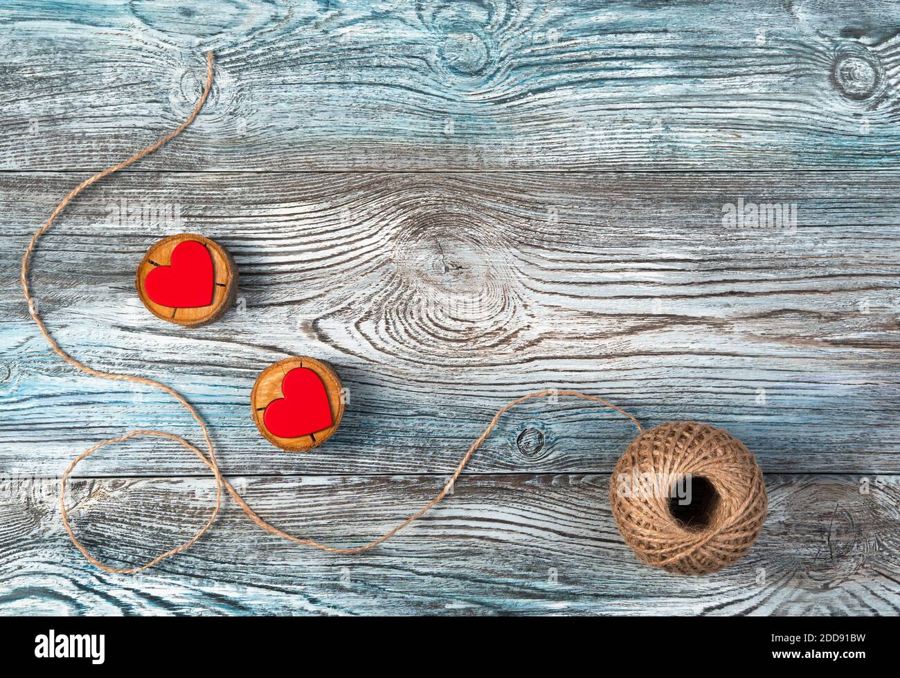 Two red hearts on wooden stands with jute thread on a wooden gray-blue ...