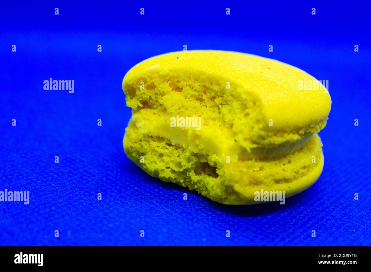 Almond macaroni bitten yellow on a blue background.Bright contrast colors Stock Photo