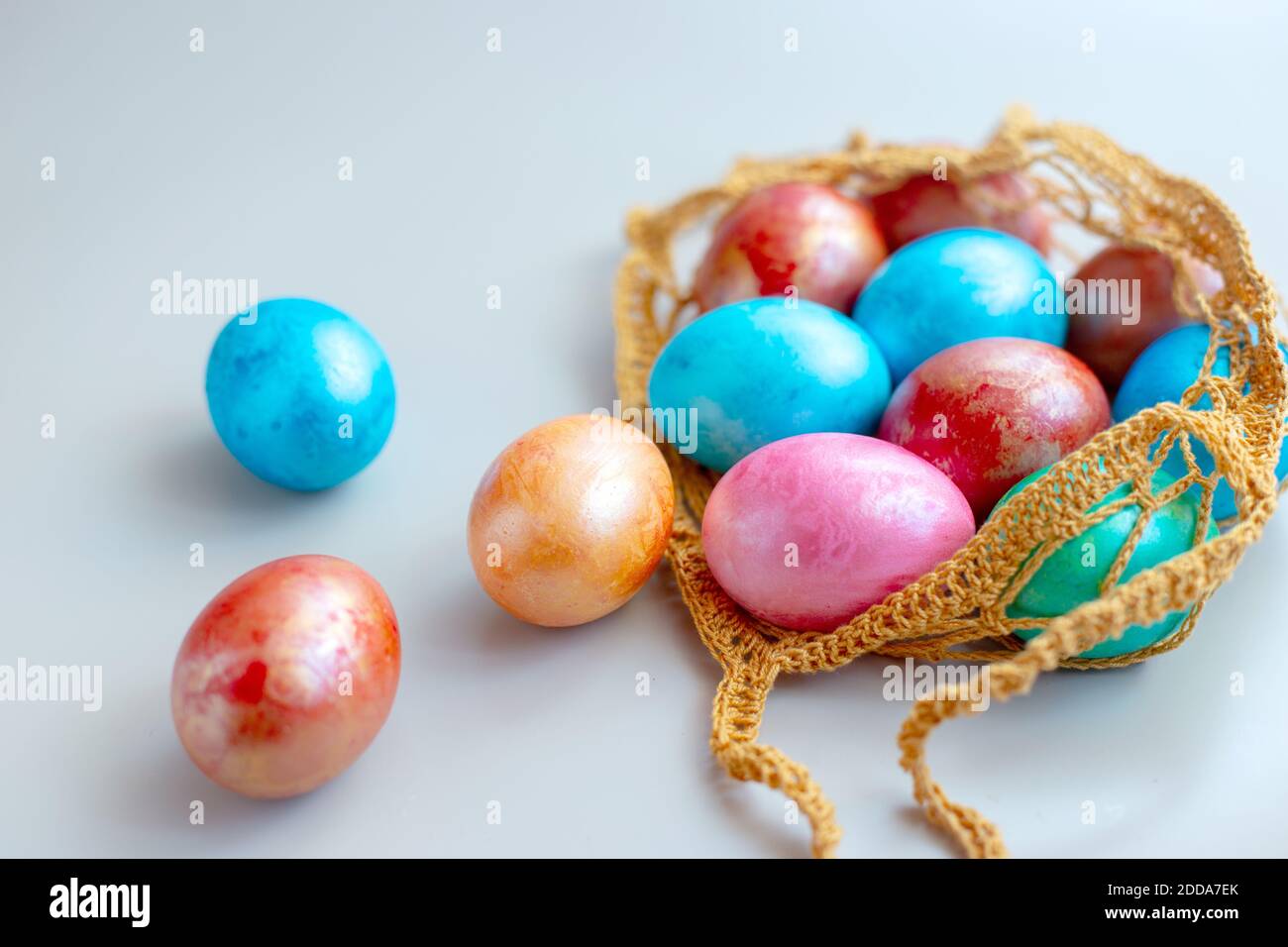 multi colored eggs in a knitted bag Stock Photo
