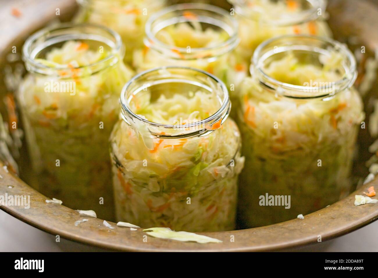 Sauerkraut fermentation in copper bowl, glass pot. Cut white cabbage