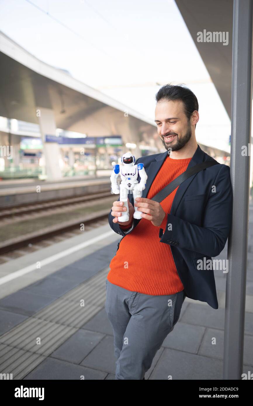 Smiling businessman looking at robot while standing on railroad platform Stock Photo