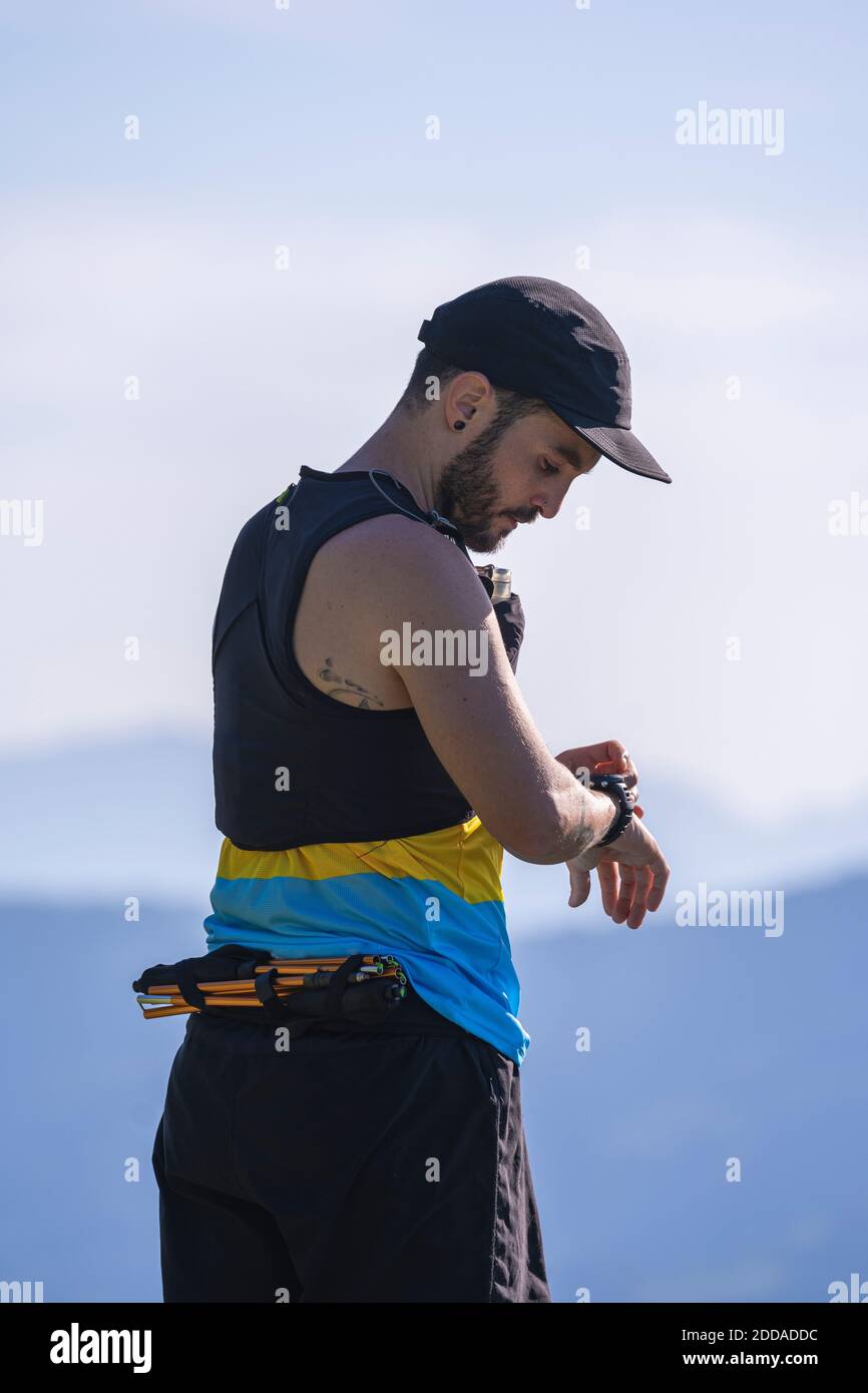 Man wearing cap checking time while standing against mountain and clear sky Stock Photo