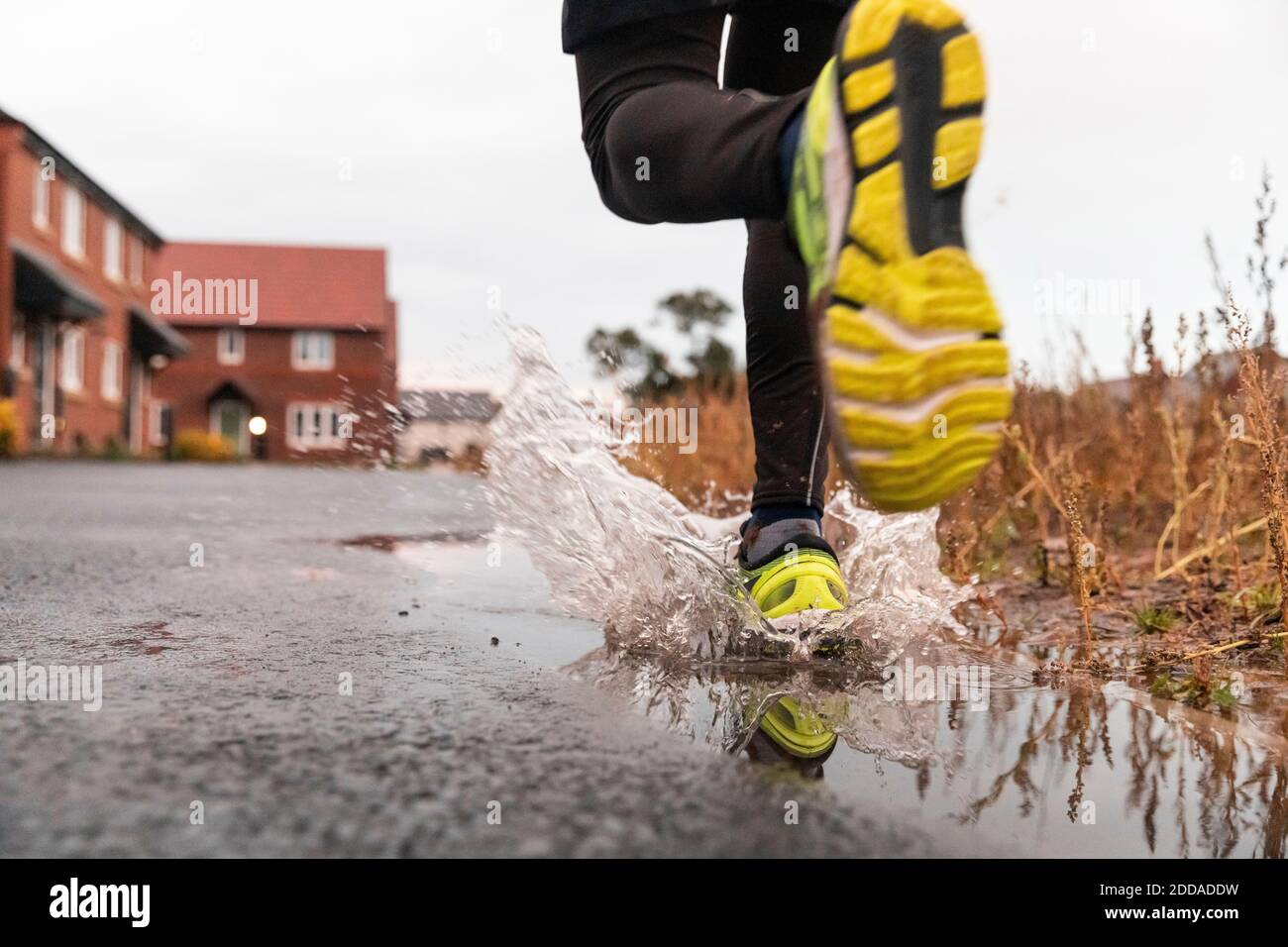 Low section of man running in water puddle during rainy season Stock Photo