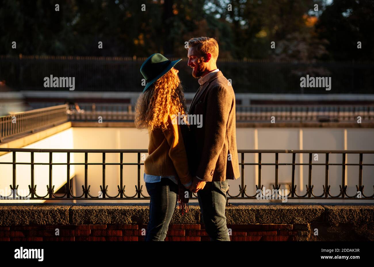 Married couple looking at each other while standing against railing at city Stock Photo