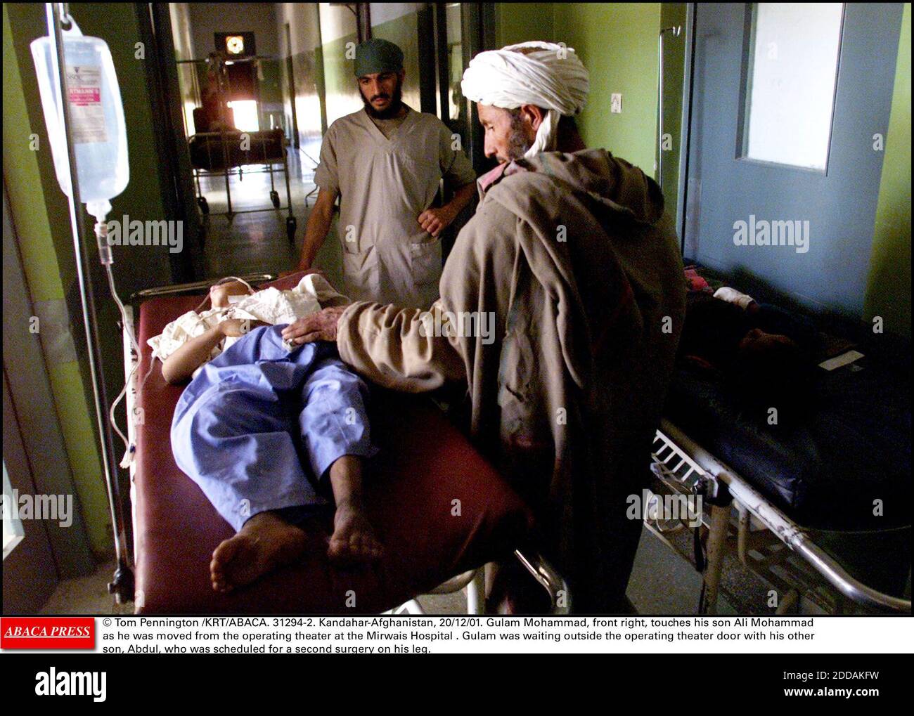 NO FILM, NO VIDEO, NO TV, NO DOCUMENTARY - © Tom Pennington /KRT/ABACA. 31294-2. Kandahar-Afghanistan, 20/12/01. Gulam Mohammad, front right, touches his son Ali Mohammad as he was moved from the operating theater at the Mirwais Hospital . Gulam was waiting outside the operating theater door with Stock Photo