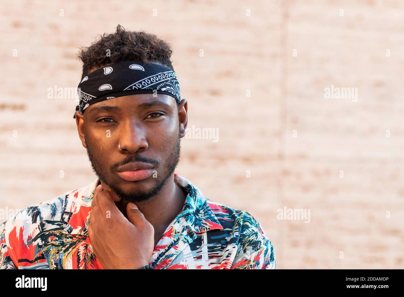 Confident young man wearing headscarf against wall Stock Photo