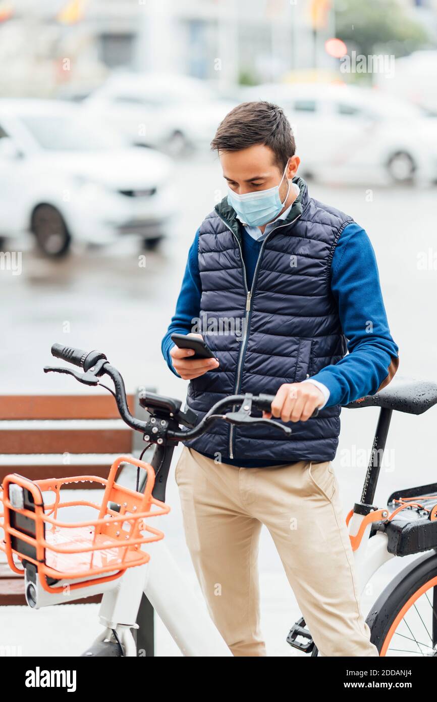 Young man with bicycle using smart phone while standing on street Stock Photo
